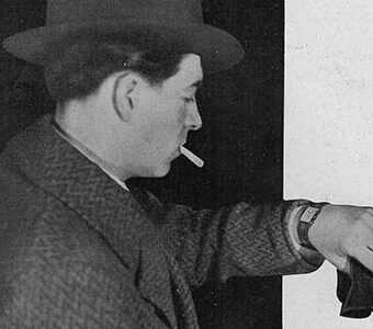 ハットに煙草をくわえ腕時計を見る男性