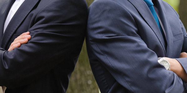 腕を組むスーツ姿の男性