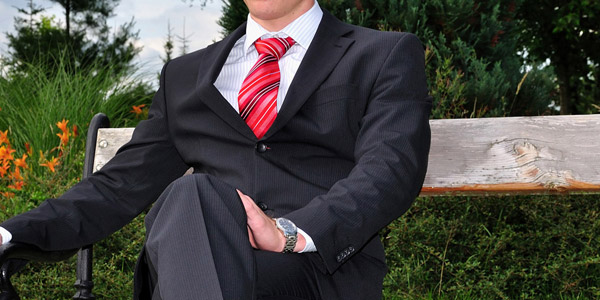 椅子に掛けるスーツ姿の男性